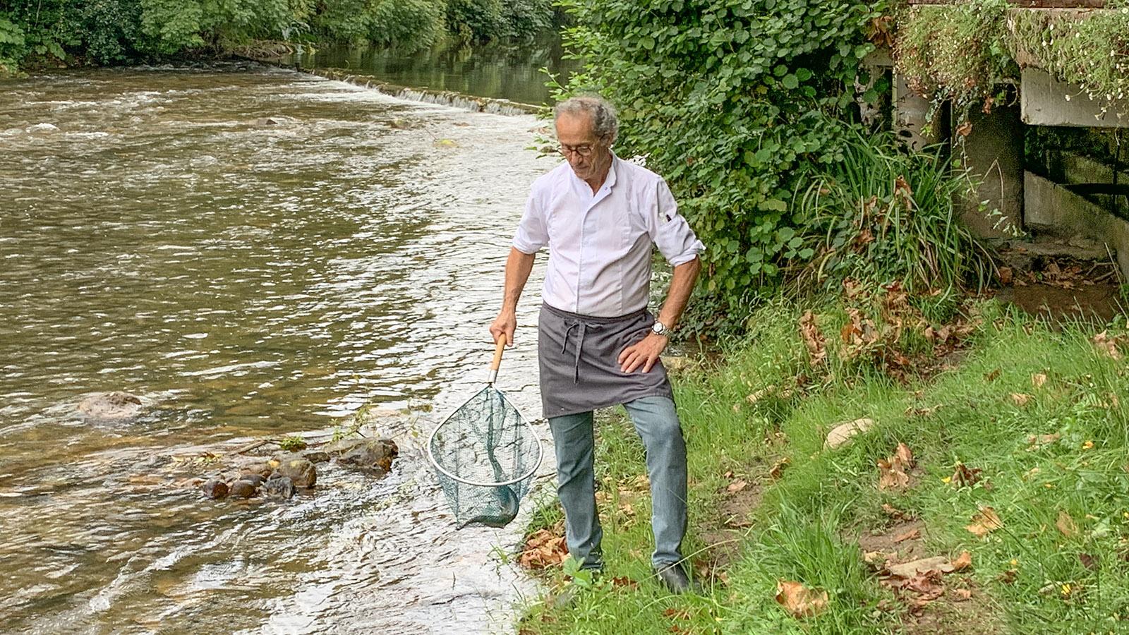 Pascale Arcé mit einer frischen Forelle. Die Zuchtbecken liegen direkt am Fluss. Foto: Hilke Maunder