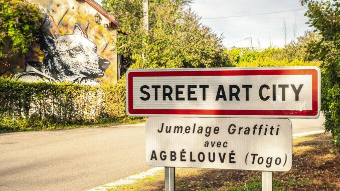 Das Straßenschild der Street Art City von Lurcy-Lévis im Département Allier. Foto: Hilke Maunder