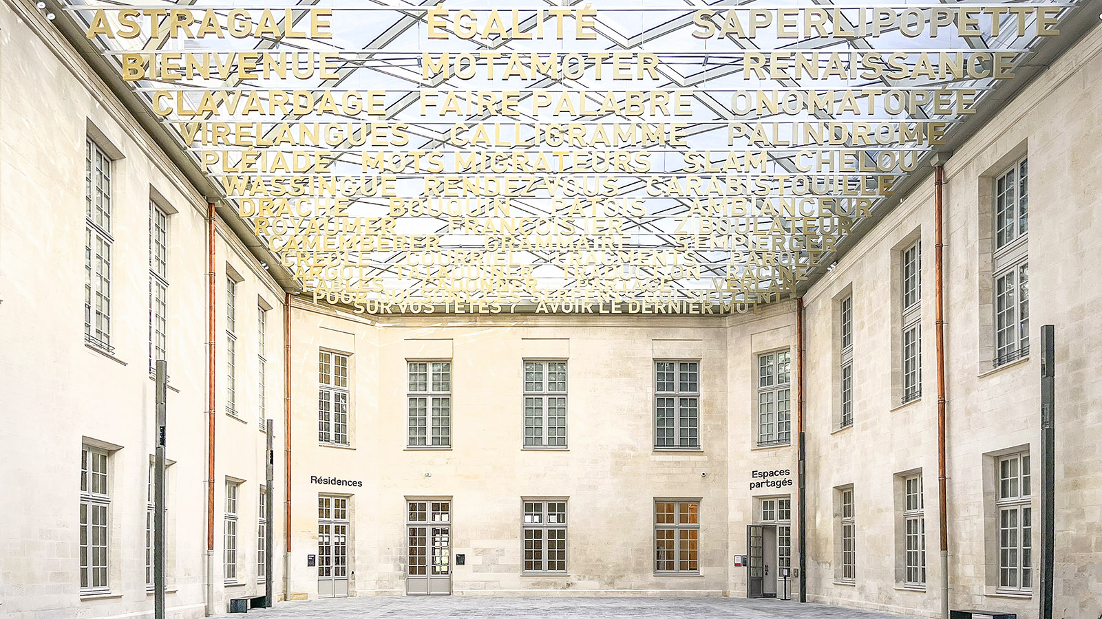 Im Lauf der Sonne spiegeln sich die Wörter auf den Fassaden im Foyer der Cité Internationale de la Langue Française. Foto: Hilke Maunder