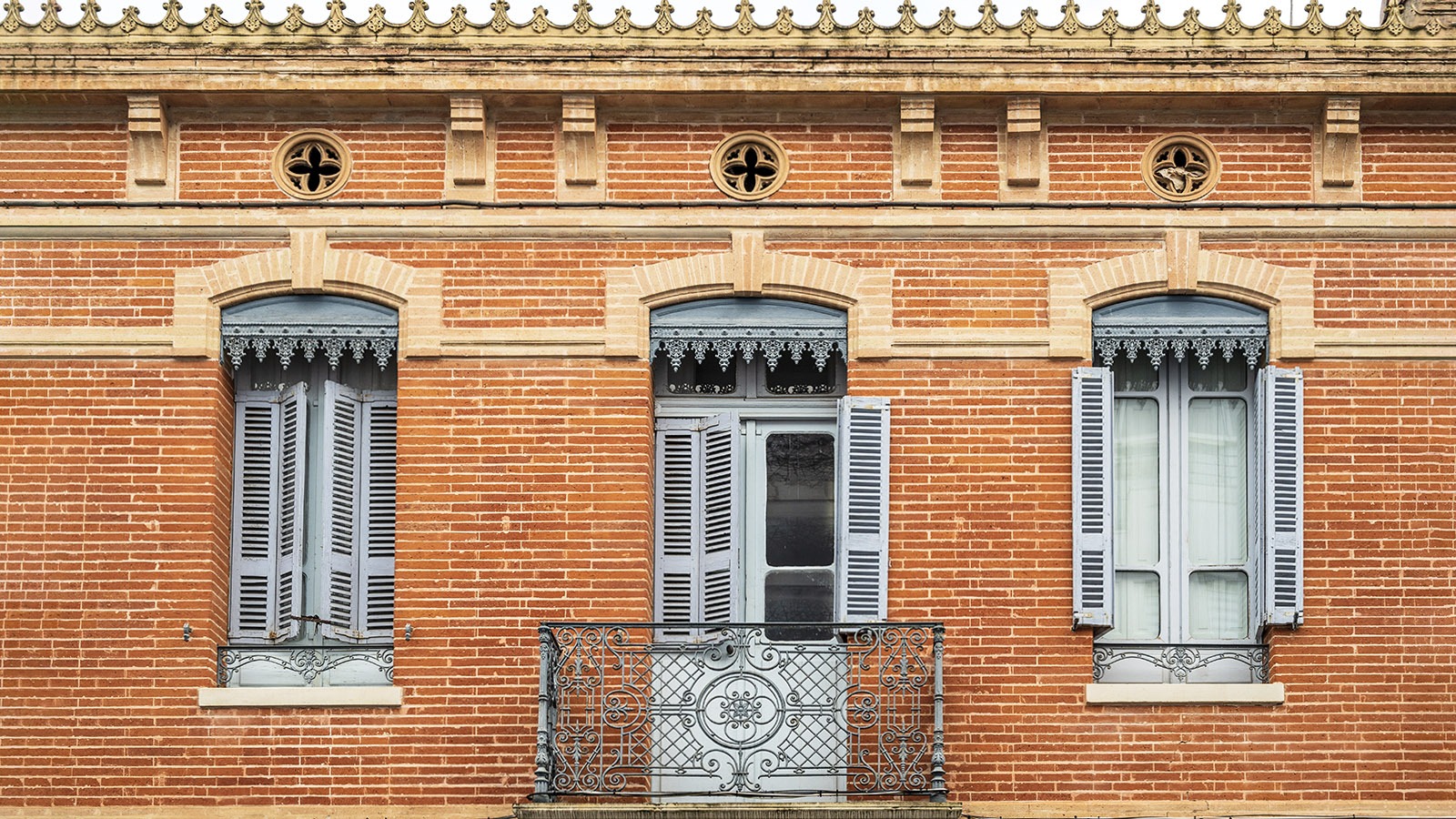 Die typische Architektur der Häuser in Toulouse: roter Backstein, Fensterläden in Pastellblau, Balkon und kreisrunde Öffnungen unter dem Dach zum Lüften des Hauses. Foto: Hilke Maunder